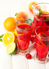 sangria in jar and glasses with fruits, on white wooden table