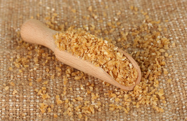 arnautka in wooden spoon on sack background close-up