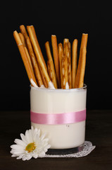 Tasty crispy sticks in glass with sour cream isolated on black