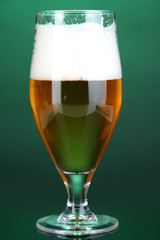 Glass of beer on green background