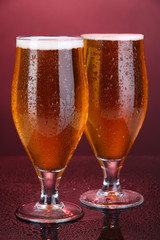 Glasses of beer on pink background