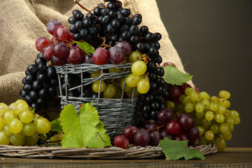 assortment of ripe sweet grapes in basket, on grey background