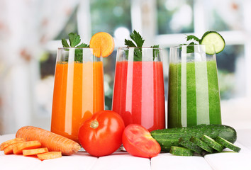 Fresh vegetable juices on wooden table, on window background