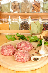 Raw meatballs with spices on wooden table