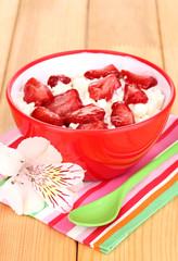 Cottage cheese in red bowl with sliced strawberries