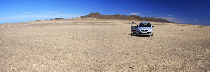 Rocky desert and car - obrazy, fototapety, plakaty
