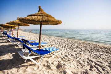 Belle plage avec chaises longues et parasols en chaume à Port El K