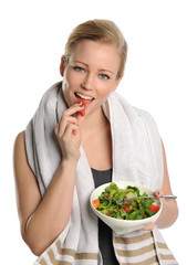 Young Woman holding a bowl of salad and eating a piece of tomato