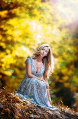 Lovely young lady wearing elegant white dress in the woods