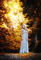 Fototapeta premium Lovely young lady wearing elegant white dress in the woods