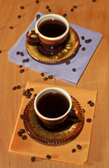 Two black cups of coffee on napkins