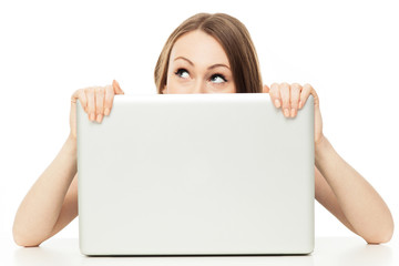 Woman looking out from behind a laptop