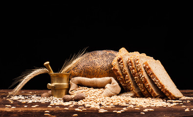 assortment of baked bread on wooden table and black background