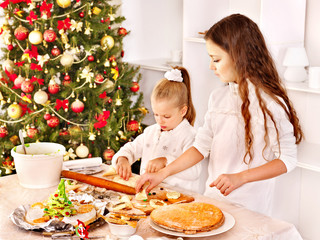 Children rolling dough in kitchen.