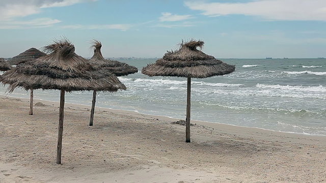 Storm the Mediterranean Sea and palm-leaf parasols on the beach
