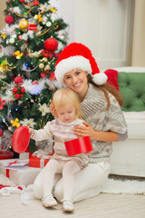 Obraz na płótnie Canvas Smiling mother holding baby opening Christmas present box