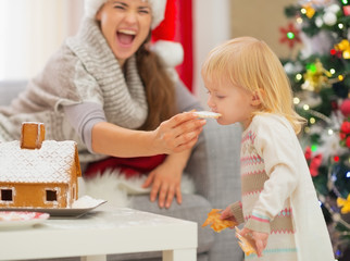 Mother giving bite Christmas cookies to baby