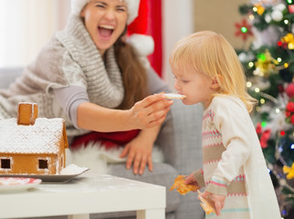 Obraz na płótnie Canvas Matka daje ciasteczka świąteczne ugryzień na dziecko