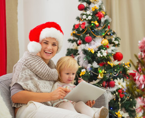 Fototapeta na wymiar Szczęśliwa matka i dziecko przy użyciu komputera typu Tablet w pobliżu choinki
