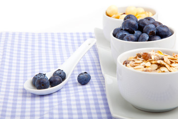 fresh blueberry in white porcelain spoon with bowl of cornflakes