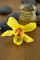 bottle of aromatherapy oil and orchid with stones