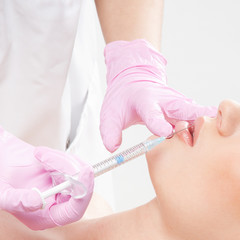 Obraz na płótnie Canvas A woman on a botox injection procedure into her lips