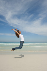 Fototapeta premium Happy woman jumping for joy at beach