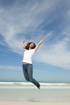 Happy pretty woman jumping for joy at beach