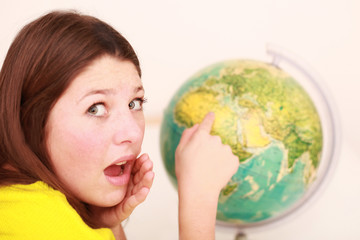 junges erschrockenes Mädchen zeigt auf die Weltkugel