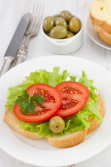 Fototapeta na wymiar toast with lettuce, tomato and olives on the plate