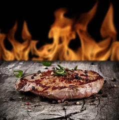 Papier Peint photo Lavable Steakhouse Délicieux steak de boeuf sur bois avec des flammes sur les arrière-plans