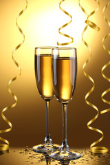 glasses of champagne and streamer on yellow background
