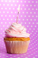 tasty birthday cupcake with candle, on violet background
