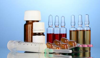 medical ampules, bottles, pills and syringes on blue background