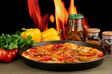 Tasty pepperoni pizza in pan with vegetables on flame