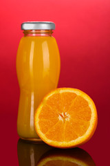 Delicious orange juice in a bottle and orange next to it