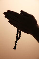 male hands with rosary, on brown background