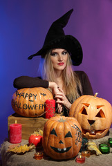 Halloween witch with pumpkins on color background
