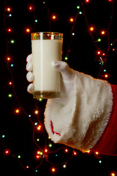 Santa Claus Hand Holding Glass Of Milk On Bright Background