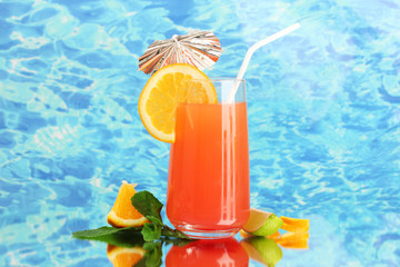Glass of orange cocktail on blue background