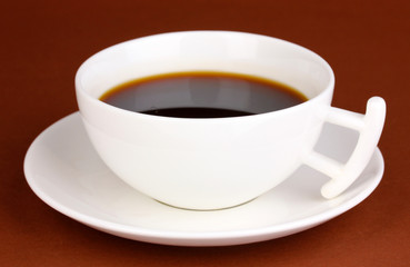 A cup of strong coffee on brown background