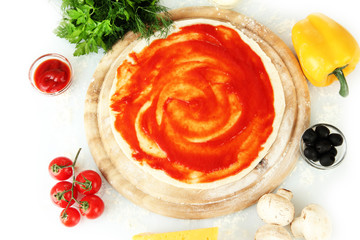 Pizza dough with tomato sauce on wooden board isolated on white