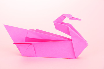 Origami swan on pink background.