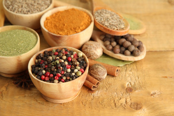 bowls and spoons with spices, on wooden background