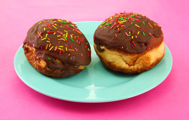 Tasty donuts on color plate on color background