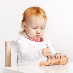 little girl playing doctor with a doll