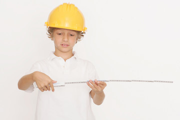 Kleiner Junge mit Bauhelm und Maßstab