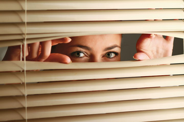 Portrait of a woman looking through out the blinds