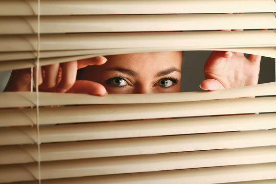 Portrait of a woman looking through out the blinds