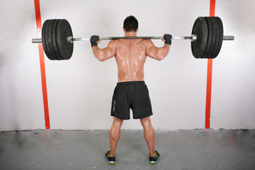 Fototapeta premium arms and back of a young muscular man working out with a bar